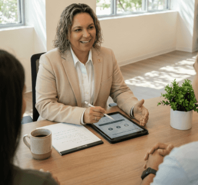 A professional woman using a tablet while discussing with clients.