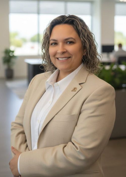 Professional woman in beige blazer smiling confidently indoors.
