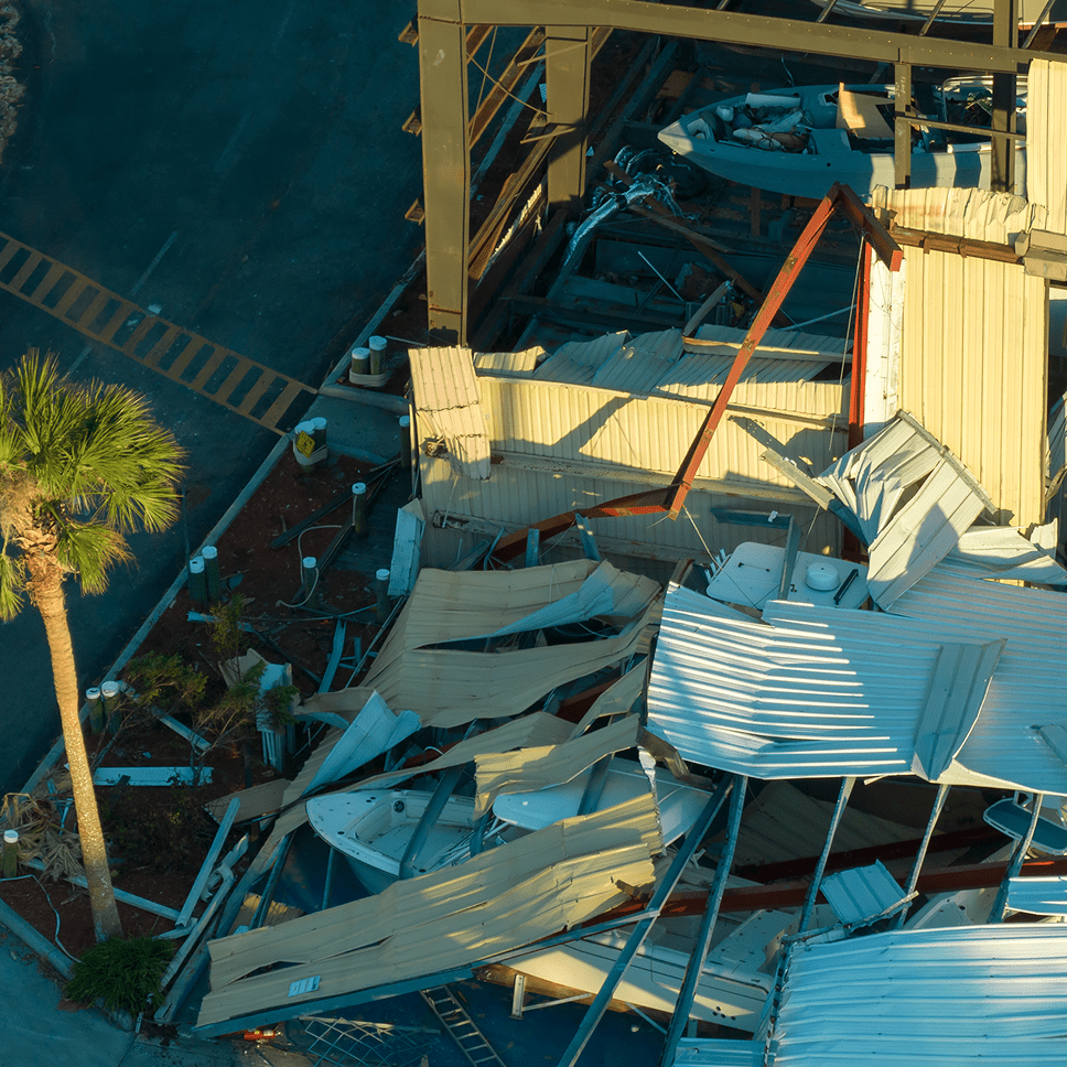 Collapsed metal roofing and debris scattered in an industrial area after damage.