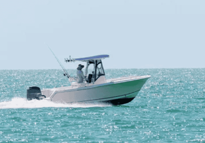A person steering a motorboat on calm waters.